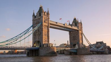 Tower Bridge spanning the Thames, viewed head-on from the water under a clear sky